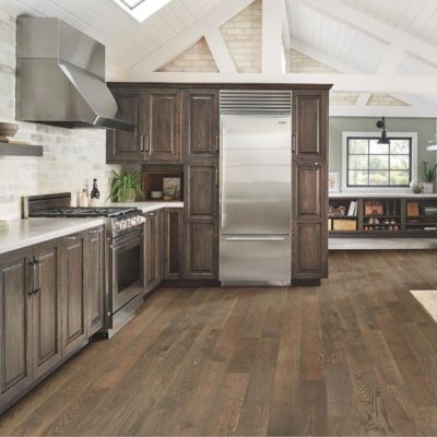 wood look laminate flooring in a rustic kitchen with dark stained cabinets and stone look backsplash